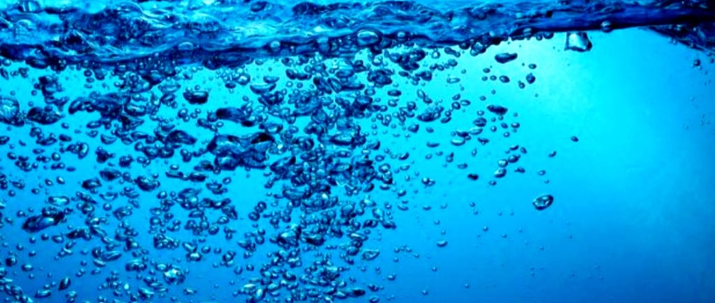 Deep blue image of crystal clear water with bubbles coming up.