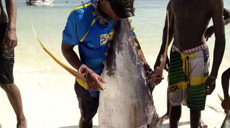 a man holding a fish on the beach