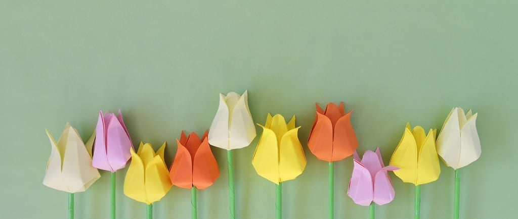 Immaginie di diversi fiori colorati su sfondo verde fatti con la tecnica degli origami