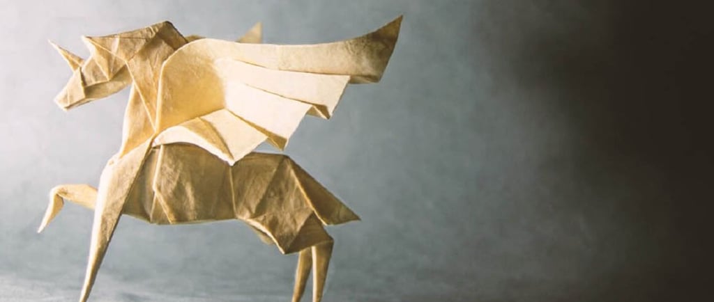 Un oriigami a forma di unicorno bianco su sfondo grigio