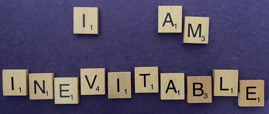 Scrabble tiles spelling out the words I am inevitable on a purple background
