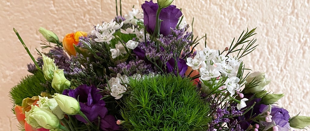 Floral bouquet with purple lisianthus, white waxflowers, and green trick dianthus.