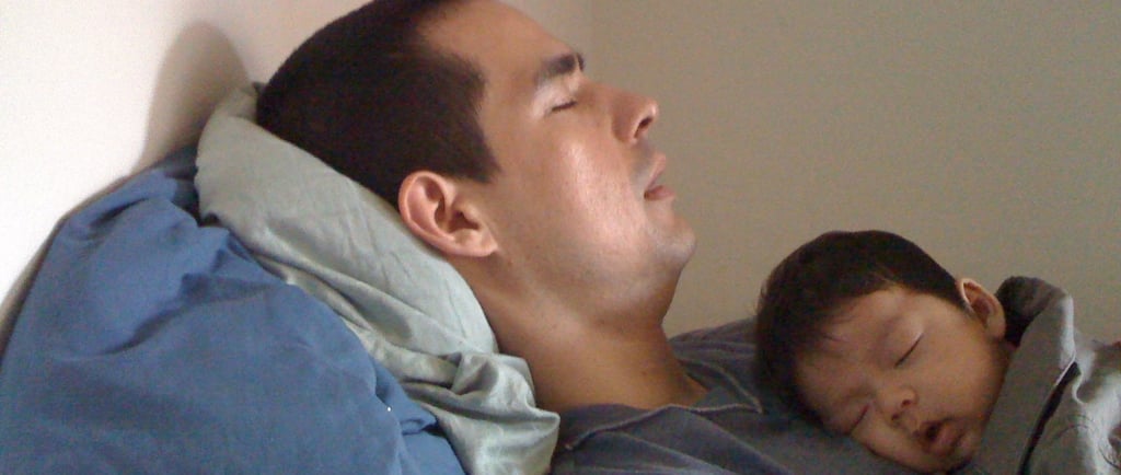 a man sleeping on a bed with a baby