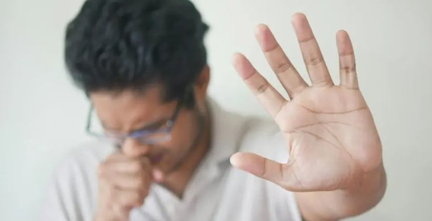 a man holding his hand up suffering from sore throat