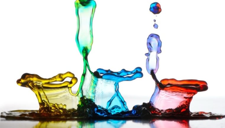 a group of colorful colored liquid paint splashes on a white surface