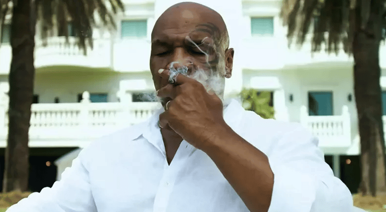 a man smoking a cigarette while sitting on a couch