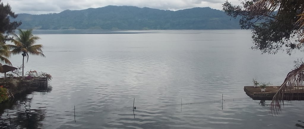 a tranquil lake with a mountain range in the background on an overcast day