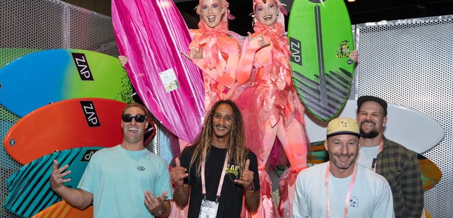 a group of people standing around two women in a costume in surf expo show