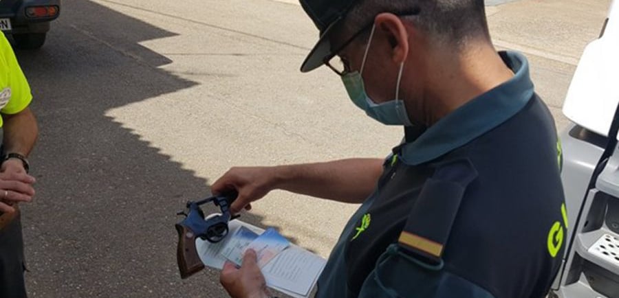 Guardia civil revisando documentación y un arma durante una inspección.