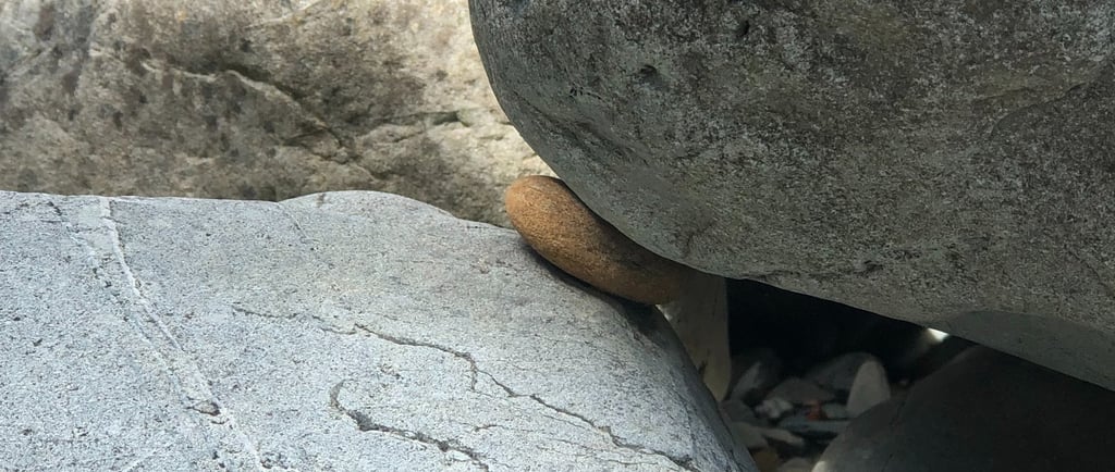 Small rock wedged between large boulders illustrating feeling stuck