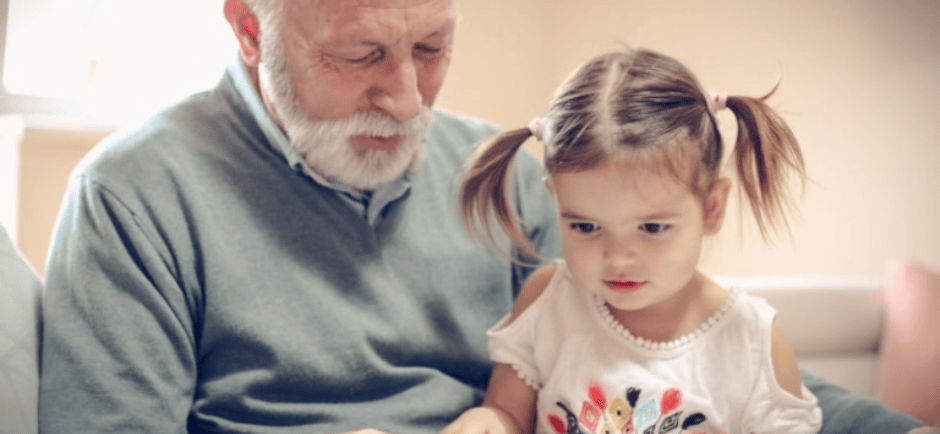 Elderly gentleman reading to a preschooler