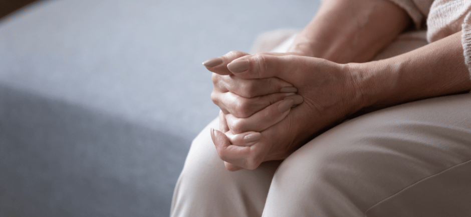 Older woman's hands clasped on her knees
