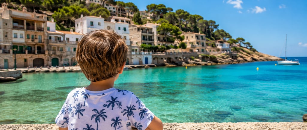 Young child looking out over the crystal-clear turquoise waters of Majorca, Spain, with a picturesqu