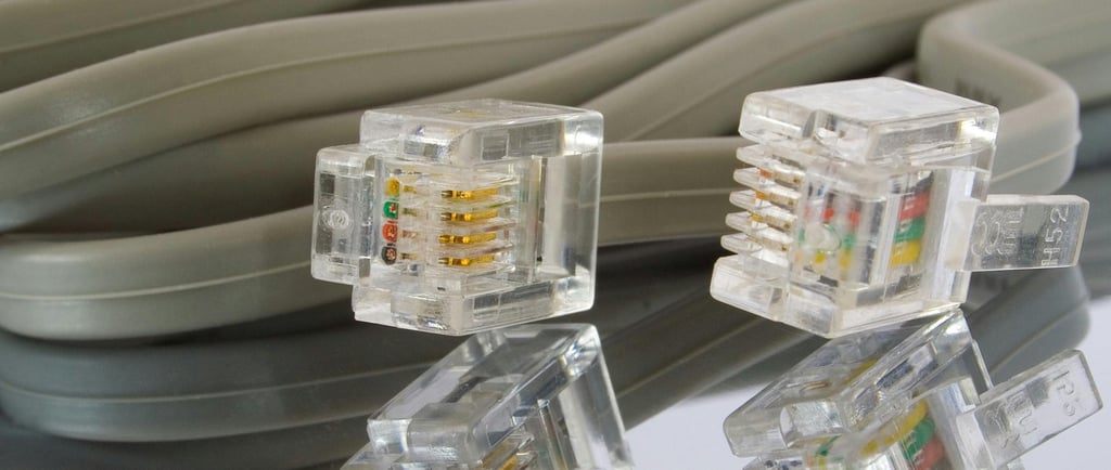 Conectores RJ45 y cable Ethernet gris reflejados sobre superficie, representando la transmisión de d