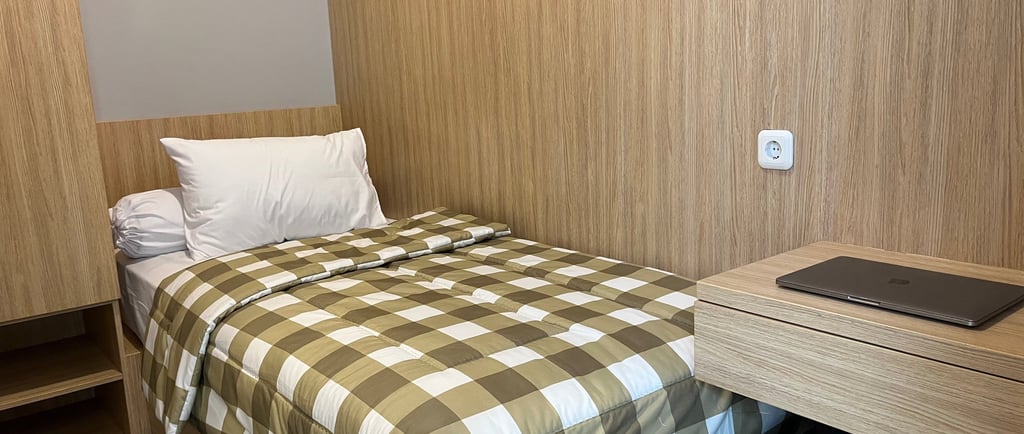Kamar kos eksklusif Kos Si Bos Surabaya dengan single bed, meja belajar, lemari kayu, dan suasana modern minimalis