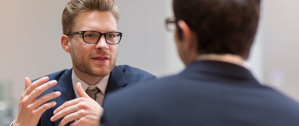 a man in a suit and tie is talking to another man