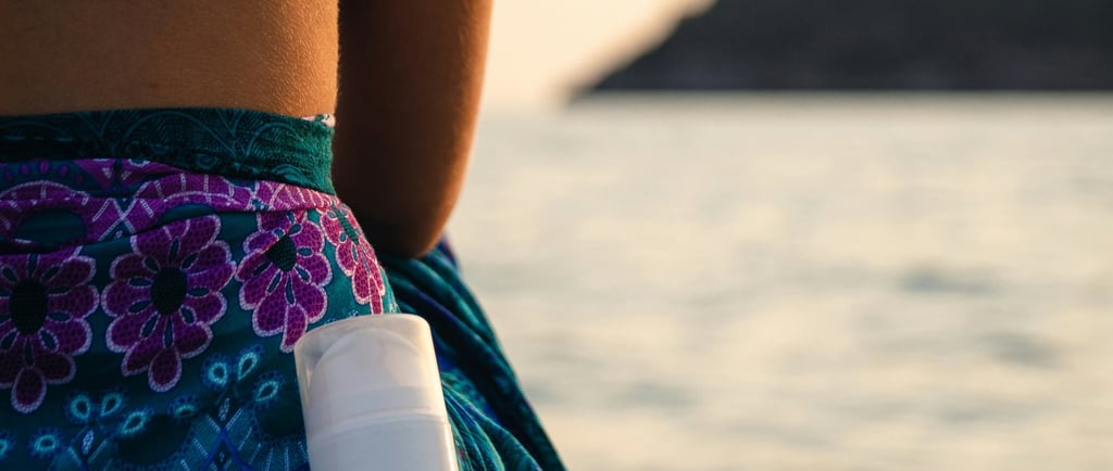 a woman sitting on a beach with a bottle of sunscreene