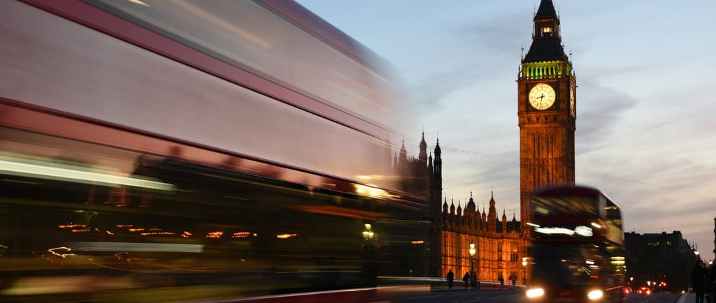 a bus driving down a street with a clock tower in the background