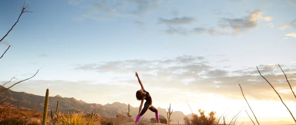 Woman doing yoga at sunrise in the desert mountains during a wild feminine awakening retreat