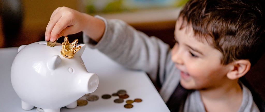 a young boy is putting coins into a piggy bank