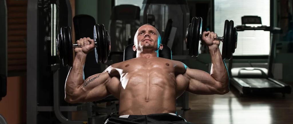 A man performing a dumbbell incline chest press exercise in a gym