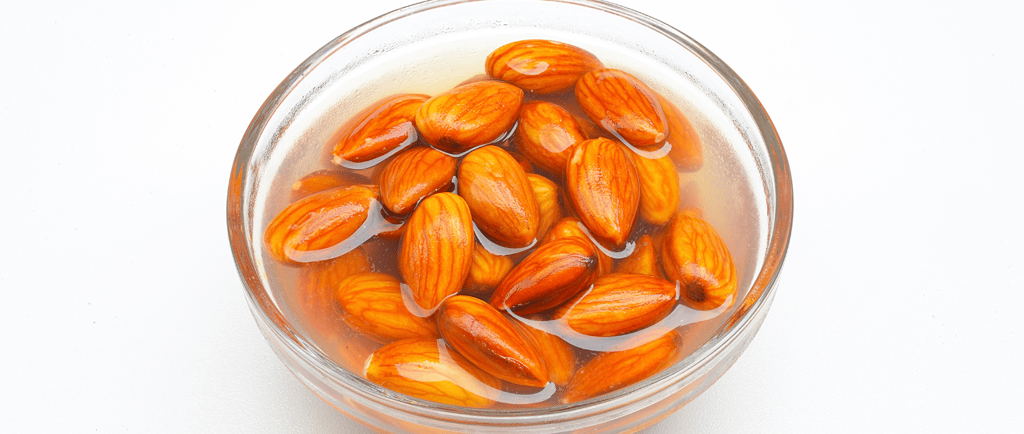 a bowl of almonds soaking in a glass bowl of water