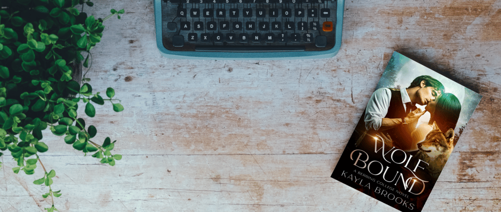 flatlay of Wolf Bound by Kayla Brooks sitting next to a typewriter and plant