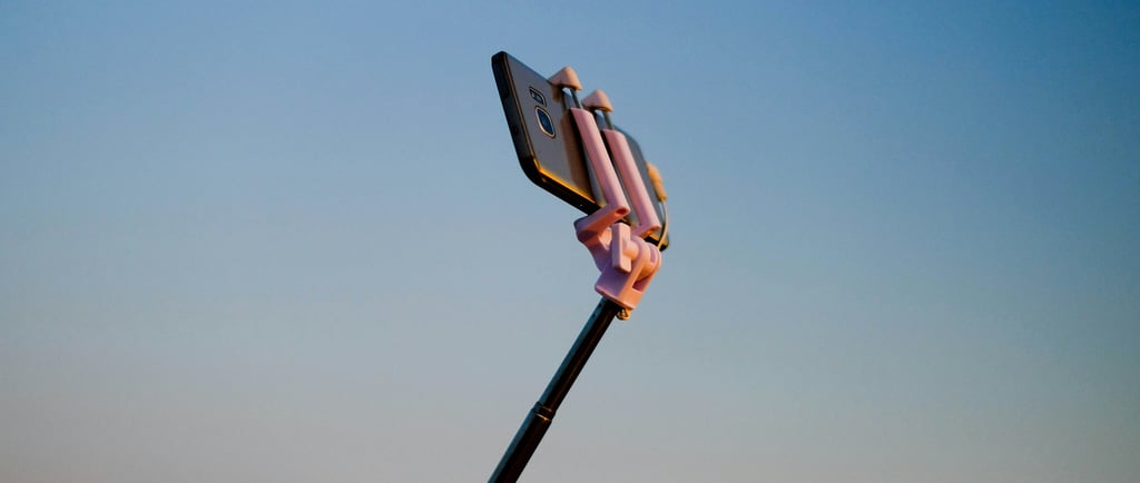 Phone on a selfie stick with blue sky background