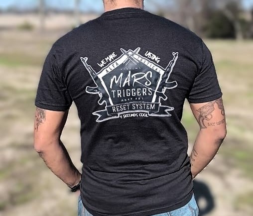 a man in a black shirt and jeans standing in a field