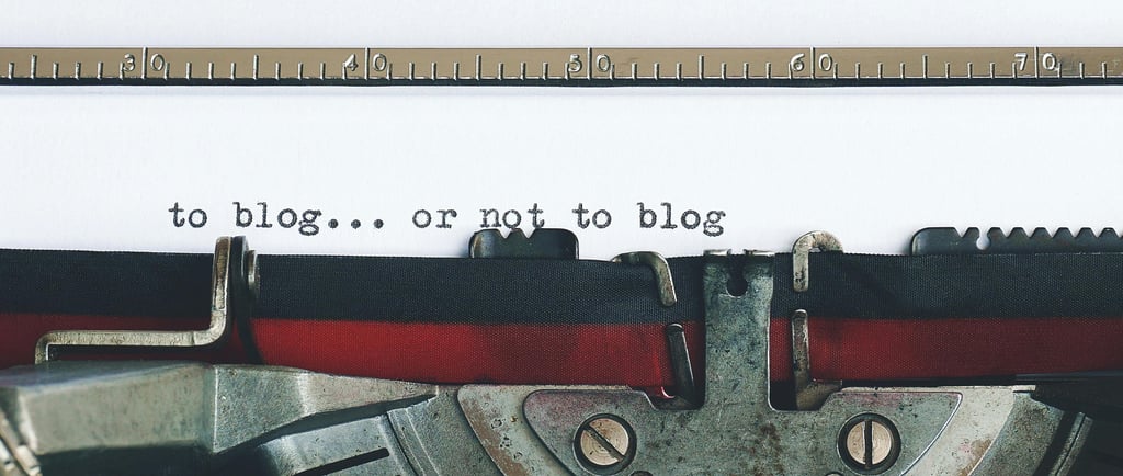 The top of a black and red typewriter, with the words "to blog... or not to blog" already typed.