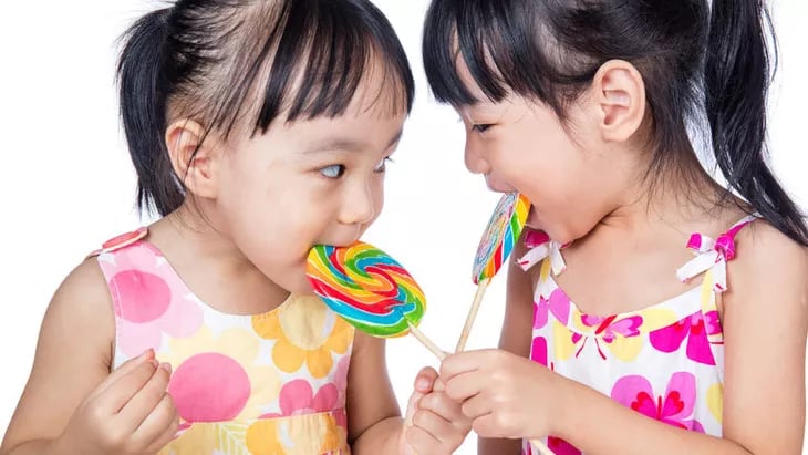 dua anak kecil yang sedang memakan permen