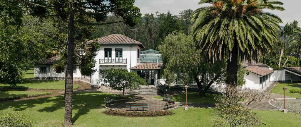 Fotografía con dron de mansión colonial de paredes blancas con techo naranja, cúpulas rodeada de naturaleza Quito Ecuador