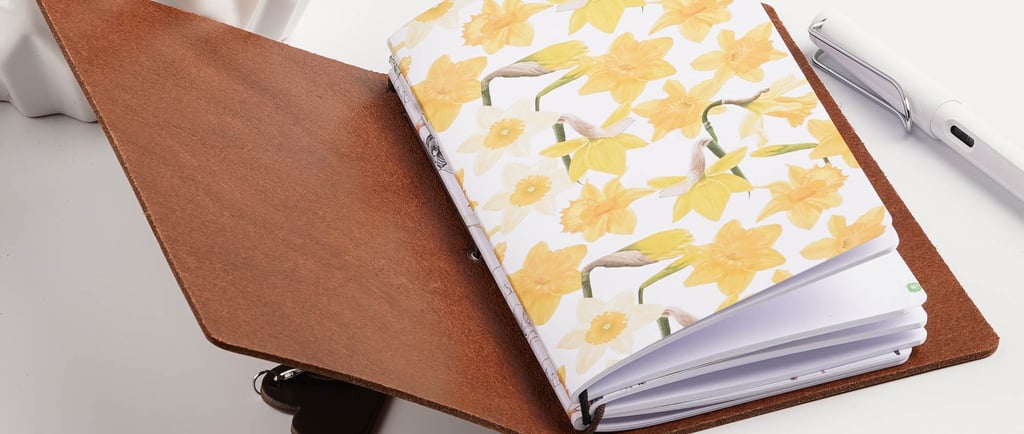 a leather journal filled with notebooks and pen on a desk