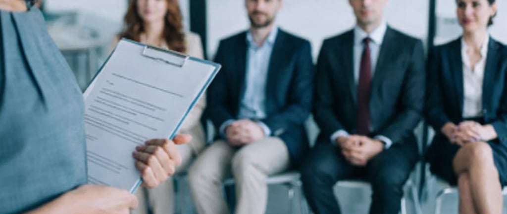 HR manager holding a clipboard while interviewing a panel of professional job candidates.