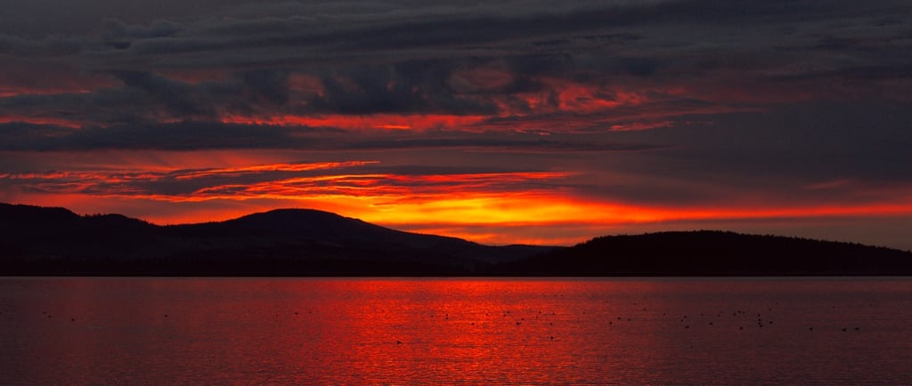 a sunset over a lake with a mountain in the background