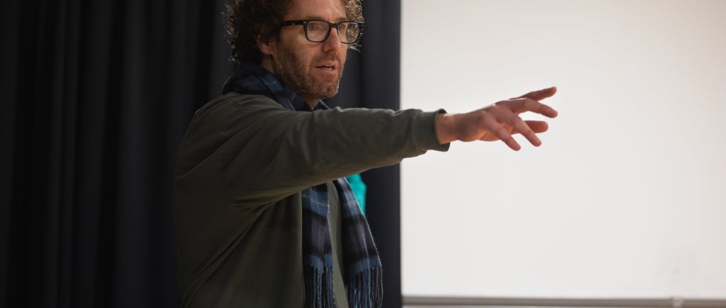 Film Director James Rose in a green jacket and scarf standing in front of actors