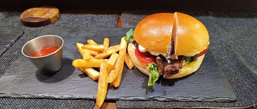 Gourmet steak burger on a brioche bun served with crispy french fries and ketchup on a slate plate.
