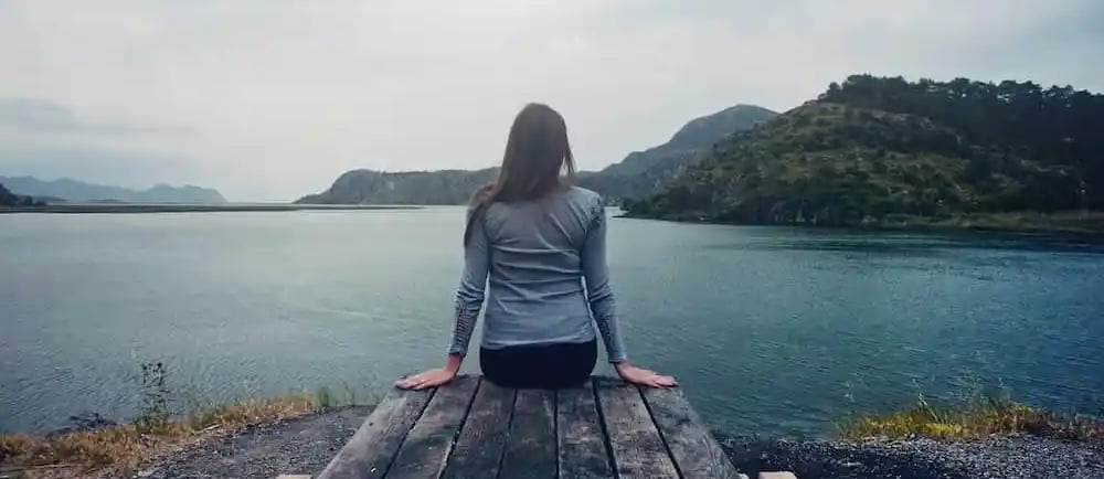femme médite au bord d'un lac