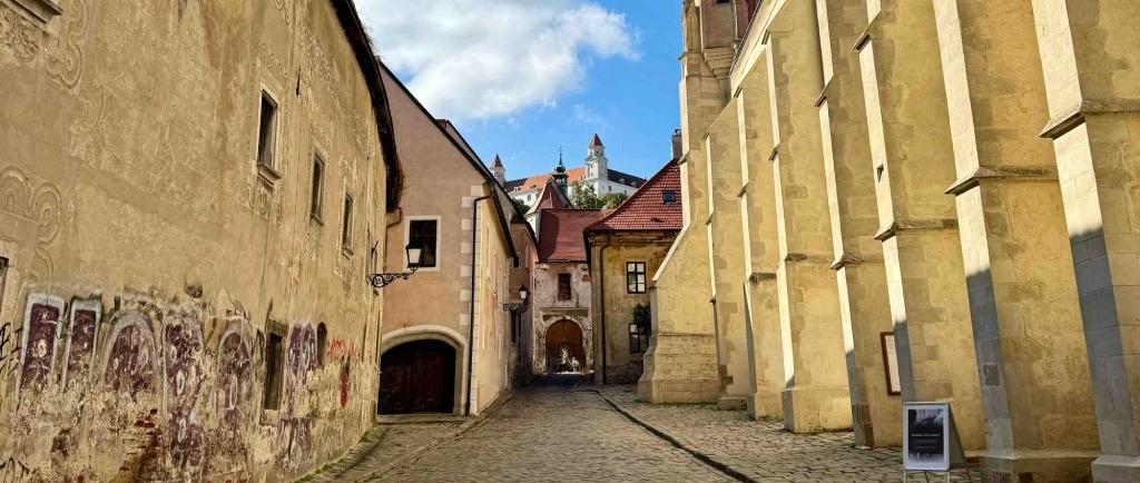 Calle adoquinada del casco antiguo de Bratislava, con fachadas históricas, vista del castillo