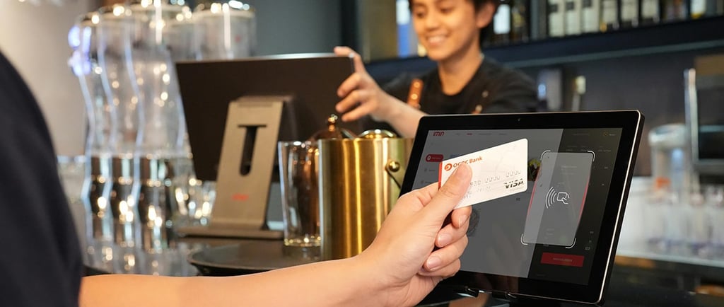 a person holding a credit card in front of a POS terminal