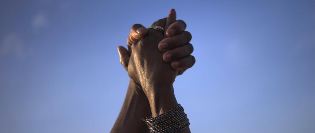 two hands holding hands with a sky background