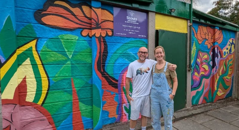 Two people outside 25th ALlerton Hut after painting a beautiful mural.