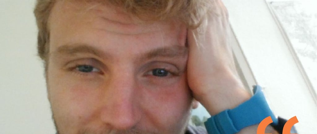 A blonde man with messy hair and a blue wristband leaning his head on his hand with a quote overlay.