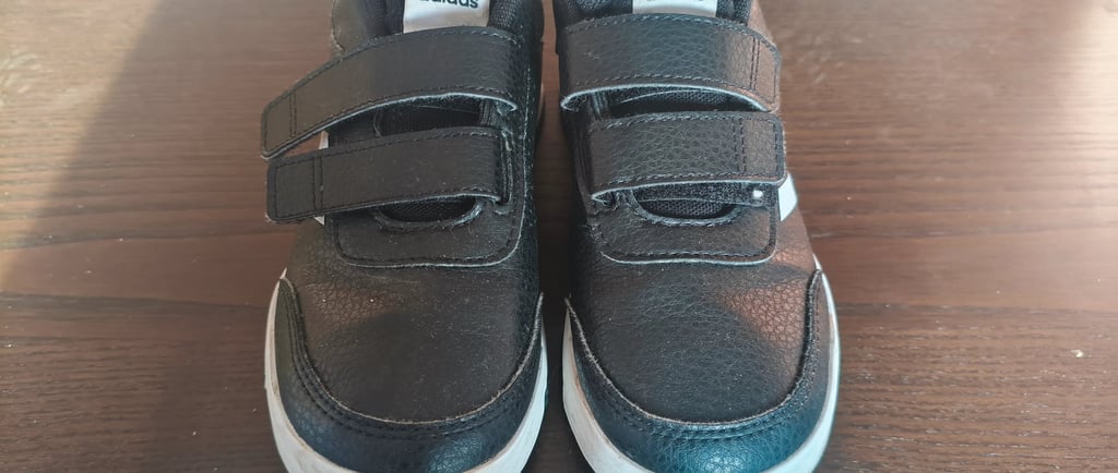 Avaliação final e ajuste das tiras de velcro em sapatilhas infantis Adidas Tensaur Sport 2.0 pretas.