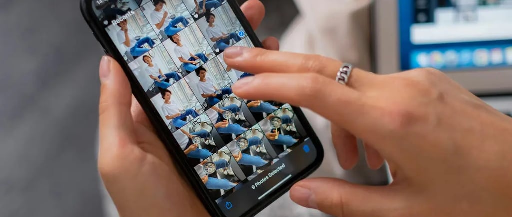 Person selecting photos on a smartphone screen next to a laptop for mobile content creation.