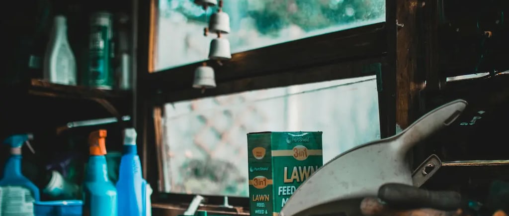 Lawn feed, weed killer, and spray bottles on a workbench in a rustic garden shed.