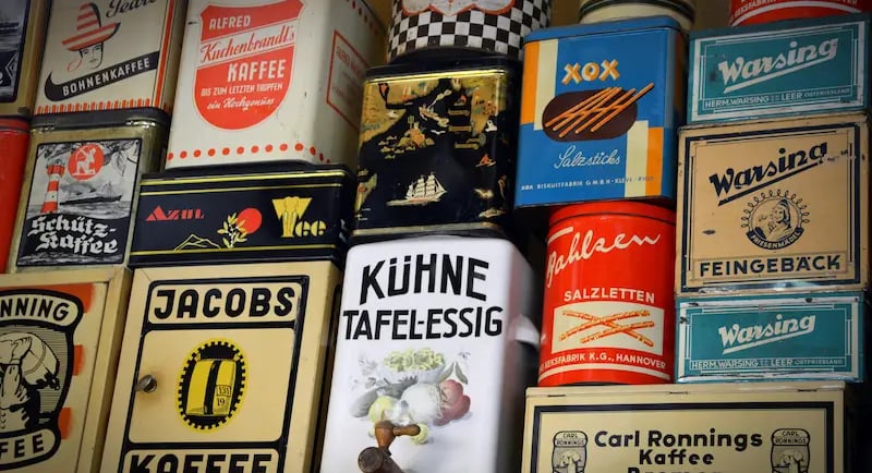 Collection of vintage coffee and snack tins with retro German branding on a shelf.
