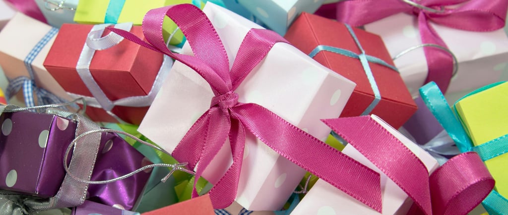 Pile of presents wrapped in paper with bows. In pink, purple, turquoise, yellow