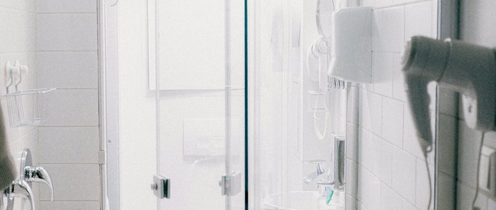 White bathroom with shower, hairdryer, basket