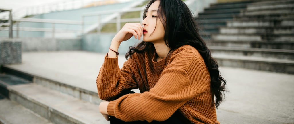 a woman sitting and thinking about her ex boyfriend and wondering if she should text him back or not